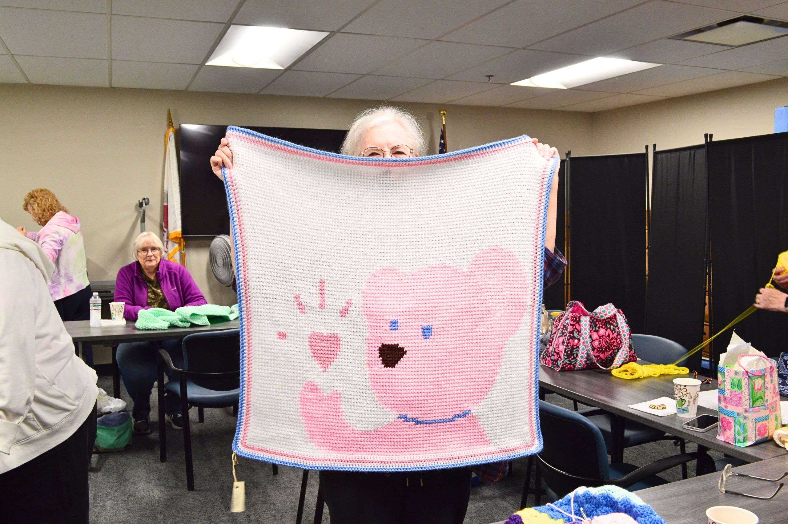 woman holding up a crochet blanket